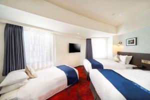 横浜市にあるベストウェスタンホテルフィーノ新横浜のベッド2台とテレビが備わるホテルルームです。