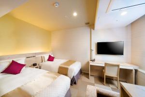 東京にあるベストウェスタンホテルフィーノ東京赤坂のベッド2台、デスク、テレビが備わるホテルルームです。