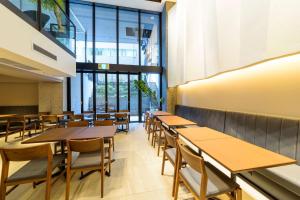 大阪市にあるベストウェスタンプラスホテルフィーノ大阪北浜の木製のテーブルと椅子、大きな窓のあるレストランを併設しています。