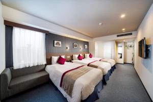 福岡市にあるベストウェスタンプラス福岡天神南のベッド3台とソファが備わるホテルルームです。
