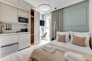 a bedroom with a large white bed and a kitchen at Downtown Apartments City Center Aura 40 in Gdańsk