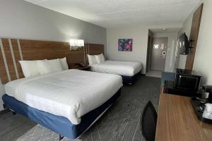 a hotel room with two beds and a television at Days Inn & Suites by Wyndham Springfield OH in Springfield