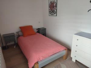 Dormitorio pequeño con cama con almohada roja en Chambre tout confort, en Landujan