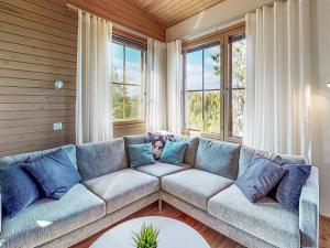 a living room with a blue couch and windows at Holiday Home Aurinkoranta by Interhome in Ruka