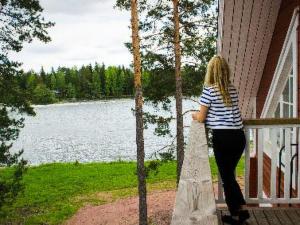 uma mulher parada num alpendre a olhar para um lago em Holiday Home Pernoo 3 by Interhome em Pernoo