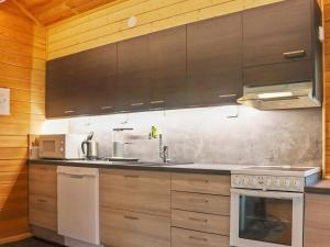 a kitchen with wooden cabinets and a stove at Holiday Home Hyryn herra cottage by Interhome in Hyrynsalmi