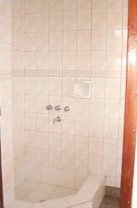 y baño con ducha y azulejos blancos. en Vivienda en altos con uso exclusivo de entrada de auto y parrilla en Miramar