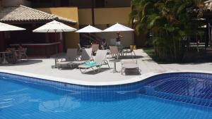 - une piscine avec des chaises longues et des parasols à côté d'un complexe dans l'établissement Praia do Forte Estúdio, à Praia do Forte