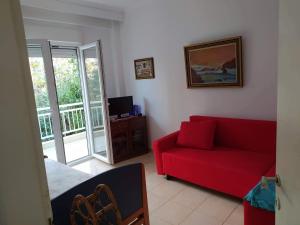 a living room with a red couch and a balcony at Wonderful and cozy 50m from the sea in Neoi Epivates
