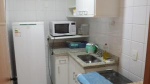 une petite cuisine avec un évier et un micro-ondes dans l'établissement Praia do Forte Estúdio, à Praia do Forte 6 autres photos