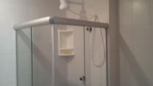 une douche avec une porte vitrée avec un porte-savon dans l'établissement Praia do Forte Estúdio, à Praia do Forte