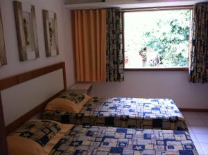 deux lits jumeaux dans une chambre avec fenêtre dans l'établissement Praia do Forte Estúdio, à Praia do Forte