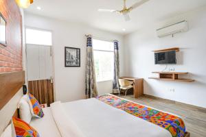 FabHotel Aravali Suites في جورجاون: غرفة نوم بسرير ومكتب وتلفزيون
