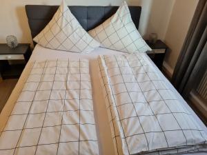 Una cama con sábanas blancas y almohadas. en Zum Goldenen Fass en Nassau