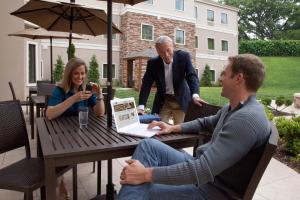 deux hommes et une femme assis à une table avec un ordinateur portable dans l'établissement Staybridge Suites Plano - Legacy West Area, an IHG Hotel, à Frisco