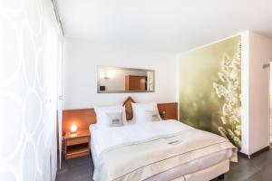 Schlafzimmer mit einem großen weißen Bett und einem Spiegel in der Unterkunft Novum Hotel Freiraum in Mönchengladbach