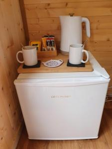 two white coffee mugs on top of a refrigerator at Gower Pods in Penclawdd