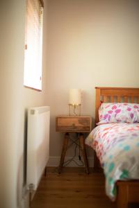 a bedroom with a bed and a table with a lamp at Stylish one bed apartment in the Stroud Valleys in Brimscombe