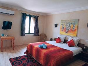 una camera con un letto con una coperta rossa e arancione di Les Jardins d Amizmiz a Marrakech
