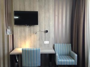a desk with two chairs and a television on a wall at Hotel Mille Colonnes in Leuven