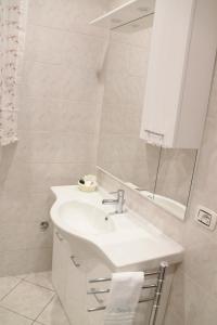 Baño blanco con lavabo y espejo en Casa di Suele, en Solarino