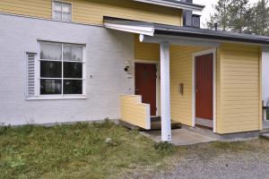 a yellow house with a red door and a porch at Economy Tieva in Levi