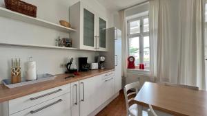 cocina con armarios blancos y mesa de madera en Villa Sonneck – Wohnung 15 en Ostseebad Sellin