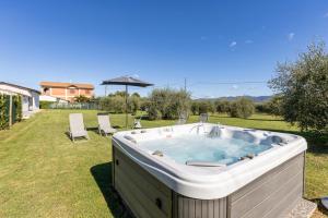 a hot tub in a yard with chairs and an umbrella at CORTONA Piscina e Paradiso Verde Adults Only in Cortona