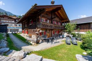 a large wooden house with chairs and a patio at Das Schmiedhaus in Kaprun