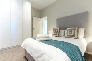 a bedroom with a large white bed with pillows at Axis Luxury Apartments by Century City Hotels in Cape Town