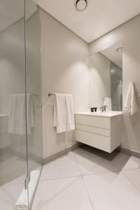 Axis Luxury Apartments by Century City Hotels في كيب تاون: حمام أبيض مع حوض ومرآة