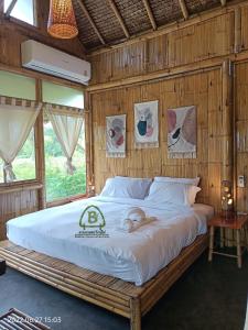 Ce lit se trouve dans un dortoir doté d'un mur en bois. dans l'établissement สวนเกษตรรักษ์ไผ่ Bamboo Conservation Farm, à Surin