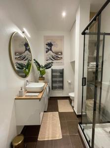 a bathroom with a sink and a glass shower at Karma Loft Barbizon - 40m2 in Barbizon