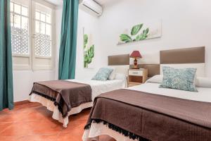 sypialnia z dwoma łóżkami i oknem w obiekcie CASA DE LA LUZ -Elegante Casco Antiguo 5-Hab w Sewilli