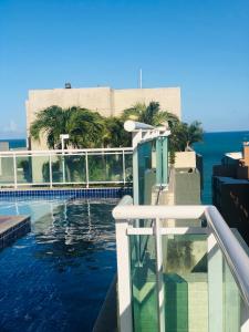 a swimming pool with the ocean in the background at Apartamento JTR Maceió in Maceió