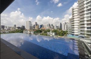 a swimming pool on the roof of a building with a city at Destiny63 Ekamai Apartment in Bangkok