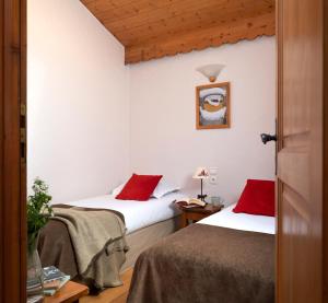 two beds in a room with red pillows at Résidence Pierre & Vacances Premium Les Alpages de Chantel in Arc 1800