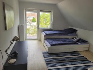 two beds in a room with a desk and a window at Strandhaus Schilksee in Kiel