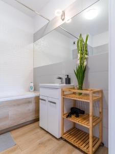 uma casa de banho com balcões brancos, um lavatório e uma banheira em FIRST -- Green Żoliborz apartment 1 em Varósvia
