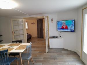 een woonkamer met een tafel en een televisie aan de muur bij Au bon temps in Coutras
