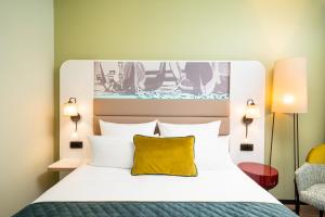 a bedroom with a large bed with a yellow pillow at Leonardo Hotel Hamburg Altona in Hamburg