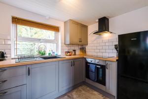 a kitchen with white cabinets and a black refrigerator at Charming 3-Bed cottage in Chester, ideal for Families & Workers, FREE Parking - Sleeps 7 in Chester