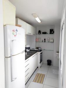 a kitchen with white cabinets and a white refrigerator at Apartamento JTR Maceió in Maceió
