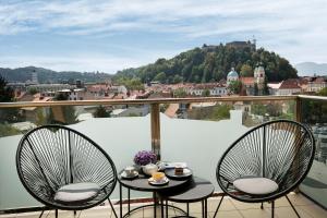 two chairs and a table on a balcony with a view at City Hotel Ljubljana in Ljubljana