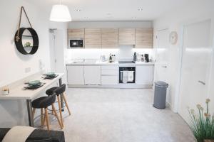 a kitchen with white cabinets and a table and chairs at Birtin Works Apartments - Brand New - City Centre in Sheffield