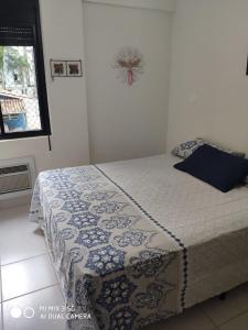 um quarto com uma cama com um cobertor azul e branco em Apartamento amplo a menos de 400 metros da praia localizado próximo a praça da Brunella, área nobre do Guarujá. no Guarujá mais 8 fotografias