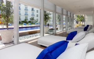Habitación con camas blancas, almohadas azules y piscina. en Hôtel Martinez, in The Unbound Collection by Hyatt en Cannes