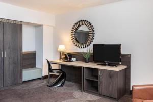 a room with a desk with a computer and a mirror at Select Hotel Handelshof Essen in Essen