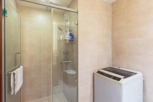 a bathroom with a shower and a washing machine at Sanya Yikehai View Apartments in Sanya