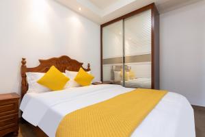 1 dormitorio con 1 cama blanca grande con almohadas amarillas en Sanya Yikehai View Apartments en Sanya